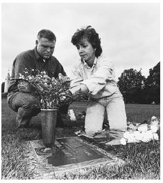 A grieving couple in Warminster, Pennsylvania, arranges flowers at the grave of their teenage son who was killed during a video store robbery. Couples with strong marital relationships prior to their child